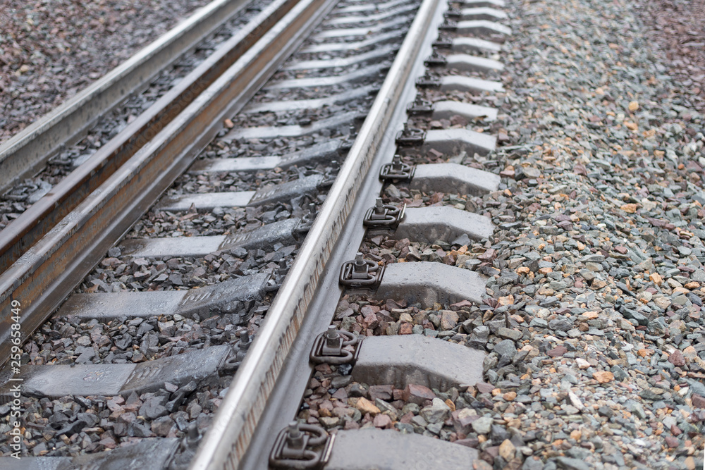 The railway with rusty elements of wear of details and damp stains from a rain , is strewn with sharp stones of rocks , in the afternoon in cloudy weather The railway with rusty elements of wear of details and damp stains from a rain , is strewn with sharp stones of rocks , in the afternoon in cloudy weather