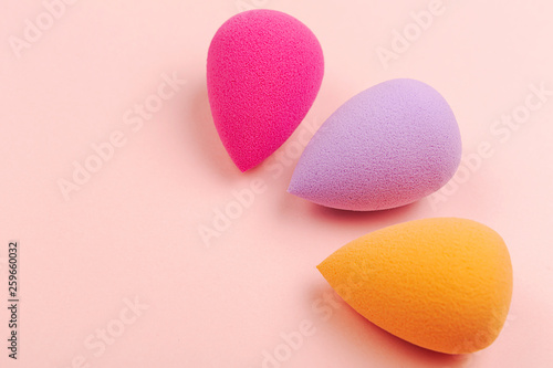 Colorful beauty sponges on pink background. Makeup tool for applying and blending products such as foundation, concealer. Horizontal shot. Copy space for text. photo