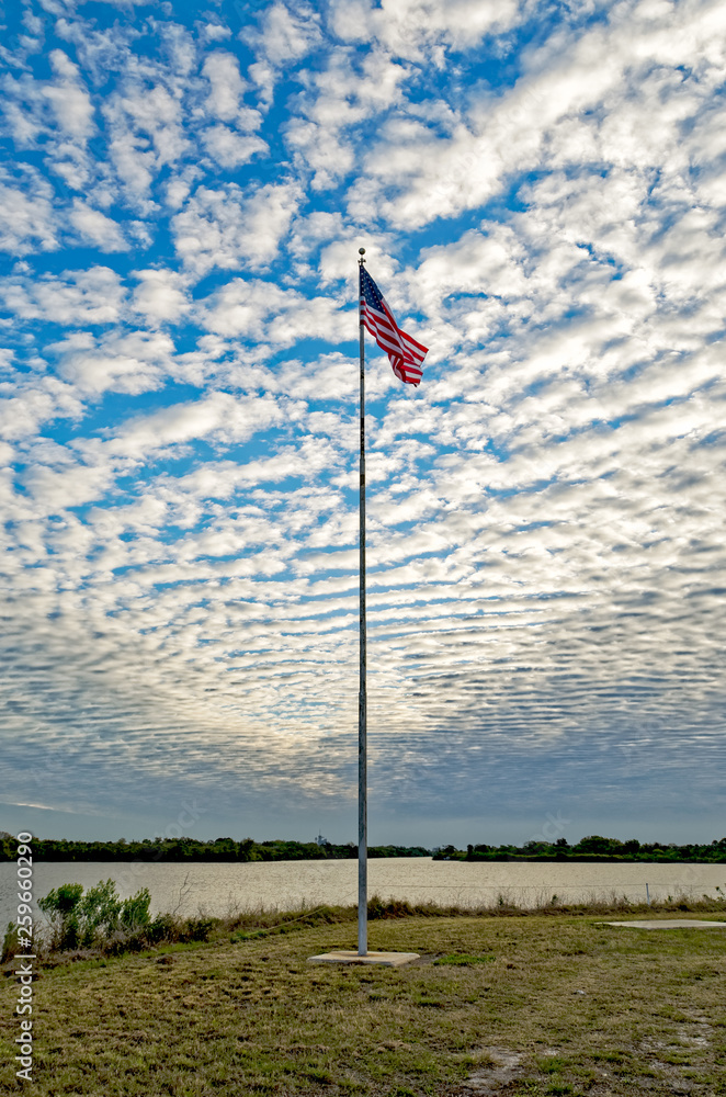 Fototapeta premium American flag wavering against morning sky in the Press Area at Kennedy Space Center