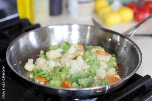 Vegetables cooking in a stainless steel pan.