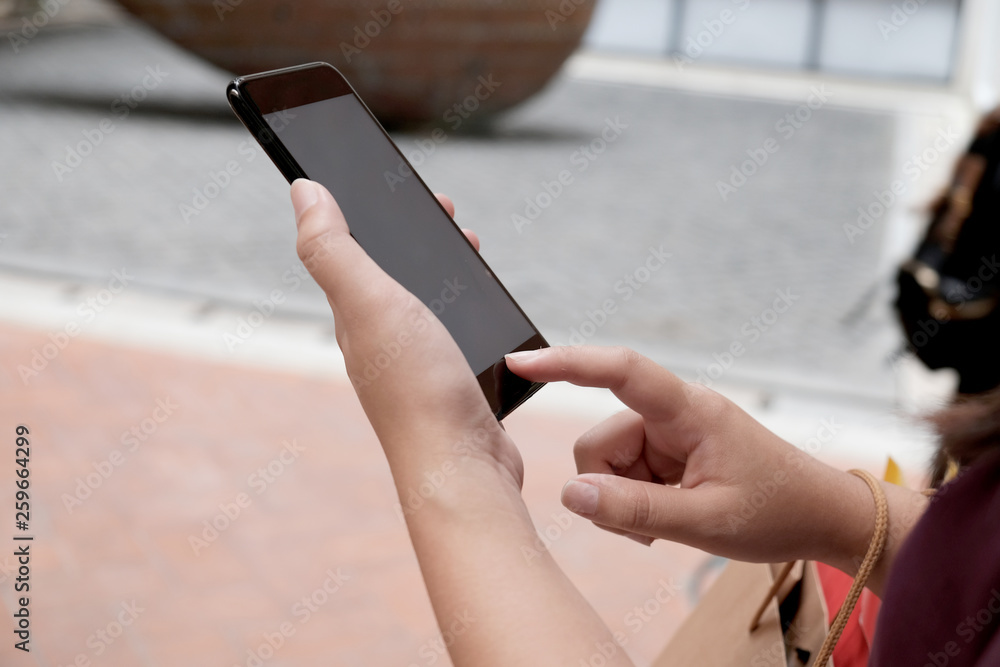 Asian girls holding sale shopping bags. consumerism lifestyle concept in the shopping mall hands holding cell telephone blank copy space screen.
