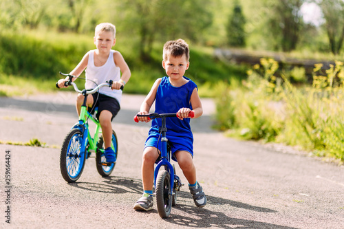 Fototapeta Naklejka Na Ścianę i Meble -  children preschoolers ride bikes in the summer in the Park on the pavement.