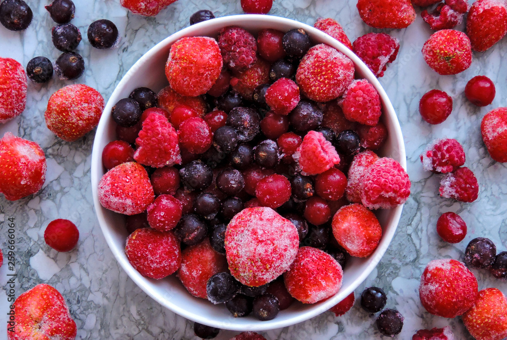 Frozen berries.Top view. Frozen delicious berries on blue background, closeup. Assorted frozen berries background. Raspberries, black currant and strawberries on blue background, copy space. Frozen berries.Top view. Frozen delicious berries on blue background, closeup. Assorted frozen berries background. Raspberries, black currant and strawberries on blue background, copy space.