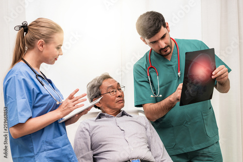 Doctor team work with x ray film image of the senior adult patient lying on the bed in the hospital ward room. Medical group teamwork and healthcare person staff service. photo