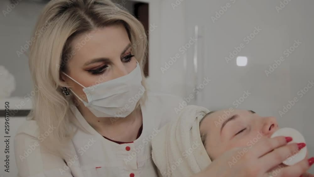 A professional cosmetologist rubs the girl's face with special moisturizing wipes. New concept in cosmetology. A professional cosmetologist rubs the girl's face with special moisturizing wipes. New concept in cosmetology.