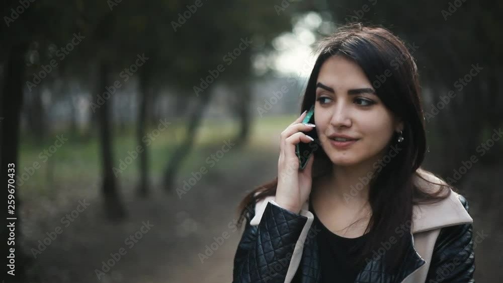 portrait of positive girl talking on the phone on the natural background
