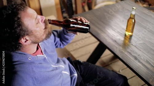 a man with a beard and mustache sniffs beer from a bottle and drinks it on a black background