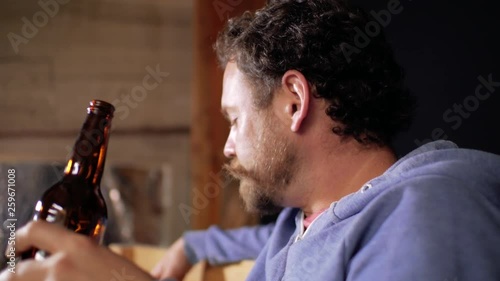a man with a beard and mustache sniffs beer from a bottle and drinks it on a black background