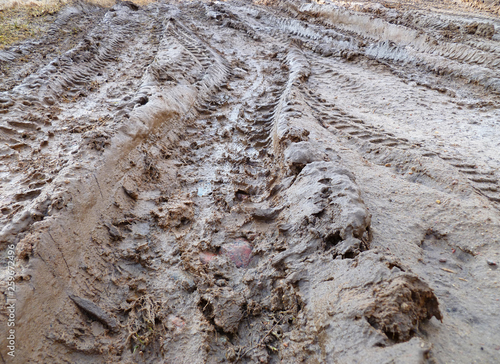 Tires deep tracks on a muddy road. Muddy dirt road in countryside with puddles filled with water and deep tracks from heavy vehicle. Tires deep tracks on a muddy road. Muddy dirt road in countryside with puddles filled with water and deep tracks from heavy vehicle.