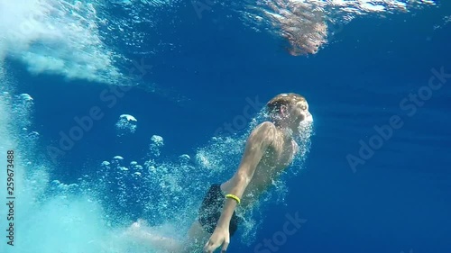 Teenage boy dives into the blue sea.  The boy swims in the Mediterranean sea under water. Slow motion. Mediterranean sea. Clean beautiful sea. 