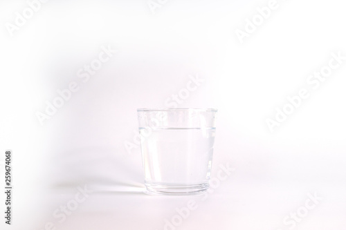 Drinking water in a clear glass on white background.