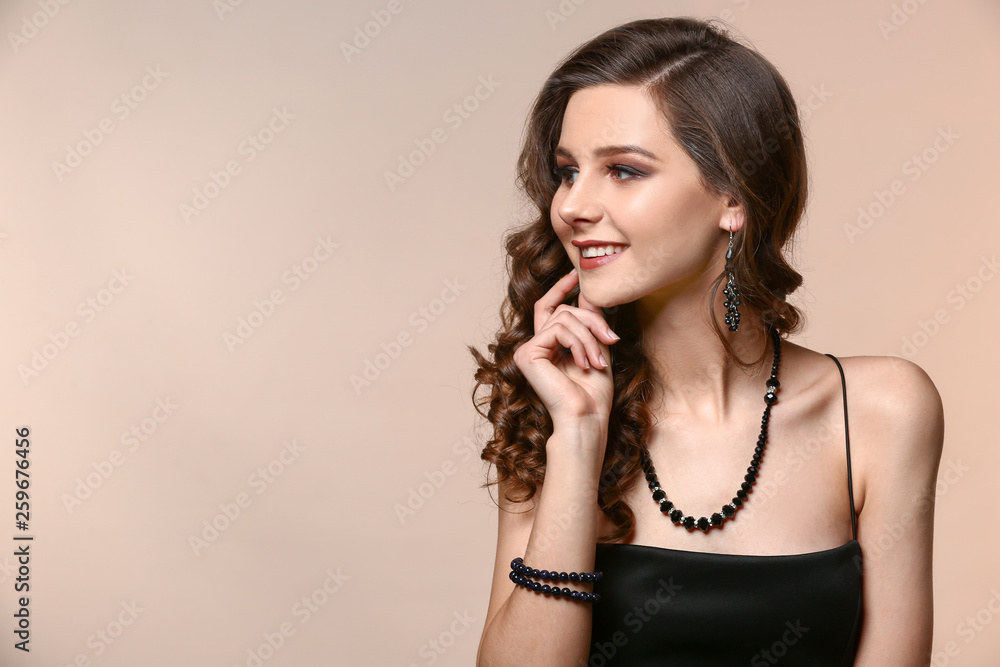 Obraz premium Young woman with beautiful jewelry on color background