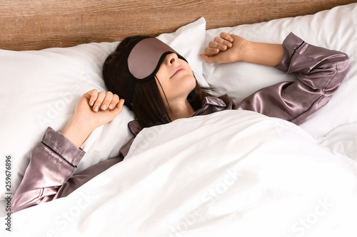 Young woman with sleep mask in bed