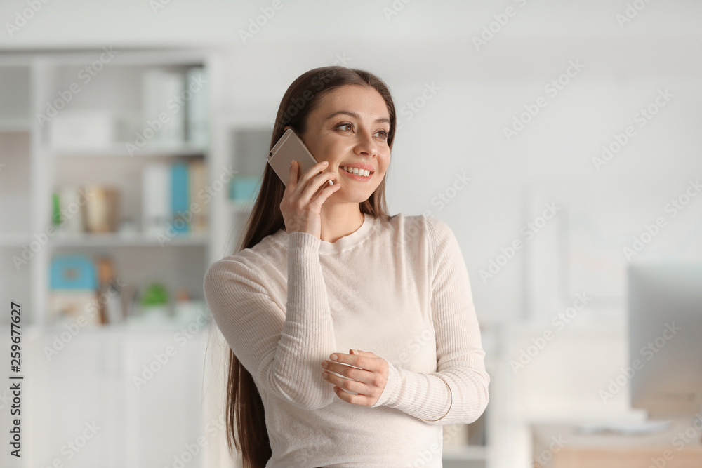Businesswoman talking by mobile phone in office Businesswoman talking by mobile phone in office