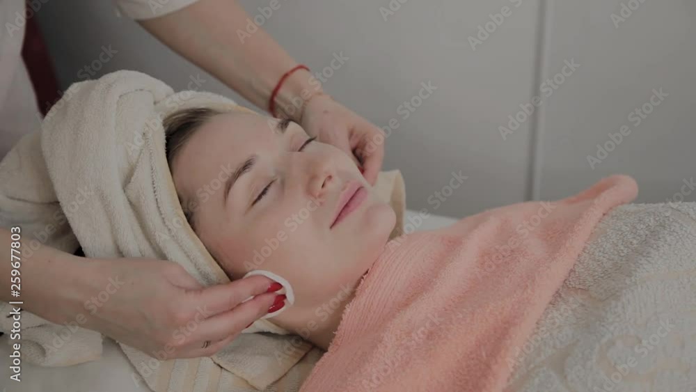 A professional cosmetologist rubs the girl's face with special moisturizing wipes. New concept in cosmetology. A professional cosmetologist rubs the girl's face with special moisturizing wipes. New concept in cosmetology.
