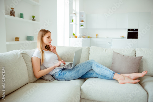 Full length body size view photo of minded dream dreamy teen serious teenager lie divan couch have fun enjoy searching news trendy wear denim jeans modern clothes in cozy comfort room
