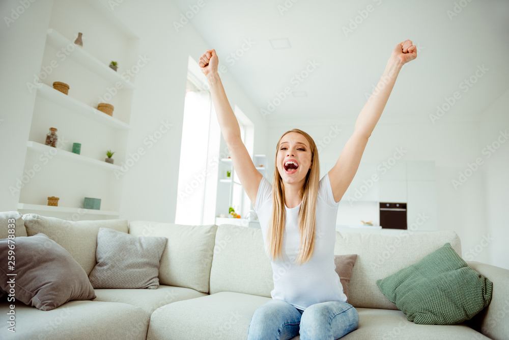 Portrait of funny funky charming lady sit divan raise fist feel satisfied cheerful delighted scream shout yeah have aims goals wear modern beautiful denim jeans t-shirts in fashionable apartment Portrait of funny funky charming lady sit divan raise fist feel satisfied cheerful delighted scream shout yeah have aims goals wear modern beautiful denim jeans t-shirts in fashionable apartment