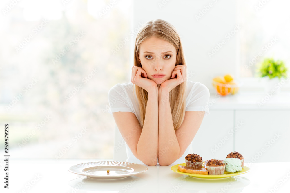 Portrait of disappointed youth hipster decide choose beautiful have problem empty dish hungry bakery confection sit table wear modern trendy outfit in big light  beautiful kitchen