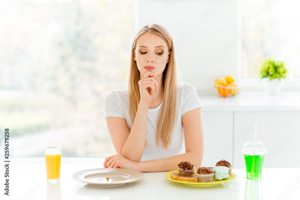 Portrait of minded serious pensive millennial decide choose vegetable have supper lunch confection muffin bakery sit in kitchen table wear trendy beautiful casual style outfit
