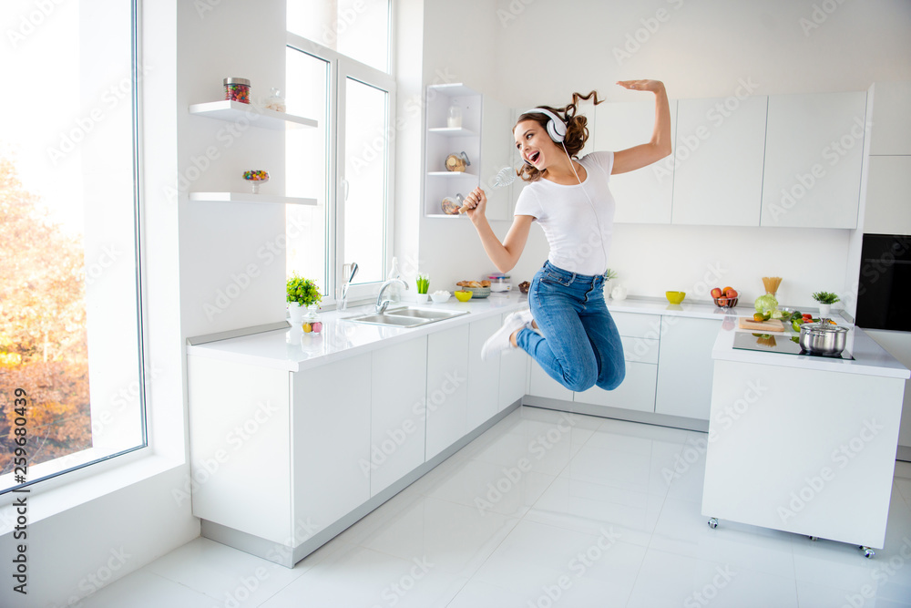 Full length body size view portrait of her she nice attractive lovely crazy childish cheerful wavy-haired girl holding in hand kitchenware like mic in modern light white interior style room Full length body size view portrait of her she nice attractive lovely crazy childish cheerful wavy-haired girl holding in hand kitchenware like mic in modern light white interior style room