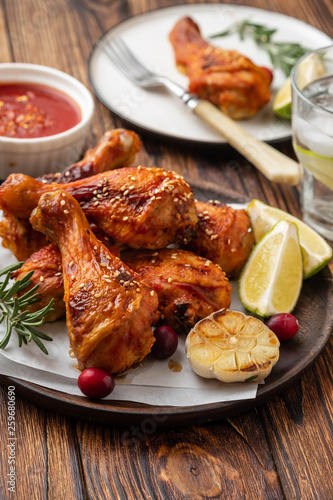 Tasty appetizing baked chicken legs served with spices, rosemary and cranberries on wooden background table. Christmas dish. Copy space.