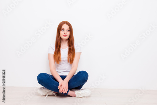 Full length body size photo beautiful she her lady tricky look empty space overjoyed long straight hair sit floor legs crossed wear casual t-shirt jeans denim outfit clothes isolated white background