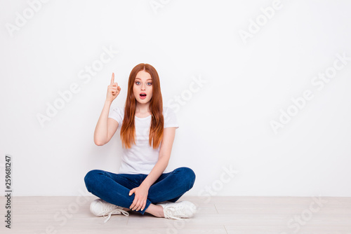 Full length body size photo beautiful she her lady sit floor legs crossed ponder pensive having idea finger raised up delight wear casual t-shirt jeans denim outfit clothes isolated white background
