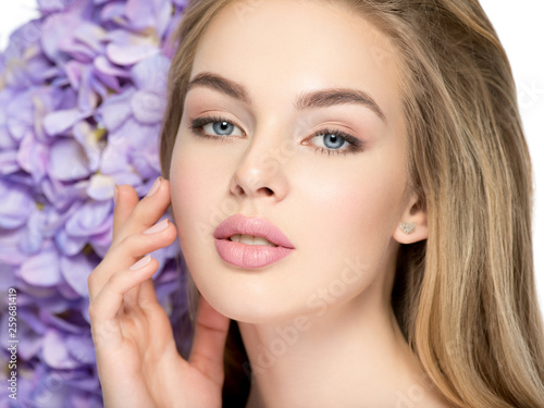 Beautiful young blonde woman with flowers near face
