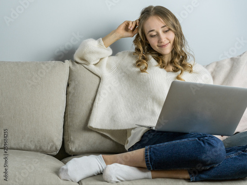 Girl sitting on sofa with laptope, hold big white mag cacao with marshmallow and listen music. Home cozy lifestile photo photo