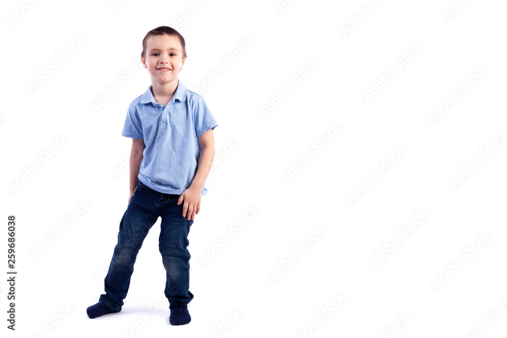 Little smiling boy with dark hair in blue jeans, blue polo t-shirt posing, laughing happily on a white isolated background in a photo studio. Portrait of happy joyful beautiful boy Little smiling boy with dark hair in blue jeans, blue polo t-shirt posing, laughing happily on a white isolated background in a photo studio. Portrait of happy joyful beautiful boy