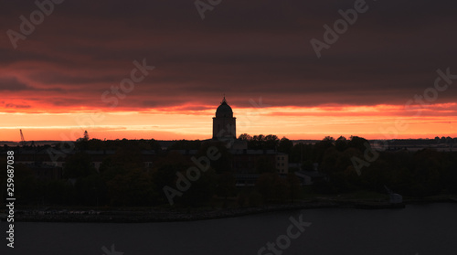 Scenic city slhouette with red sunset and dark mood at spring evening in Helsinki, Finland. Suomenlinna tower silhouette.