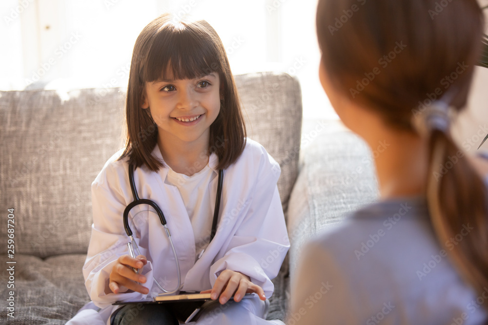 Little girl wearing doctor white coat playing doctor with mother Little girl wearing doctor white coat playing doctor with mother