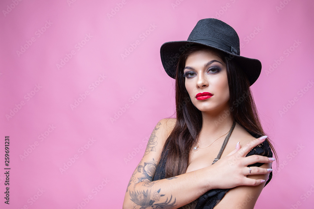 Cute young girl posing on pink background in black swimsuit and capes Cute young girl posing on pink background in black swimsuit and capes