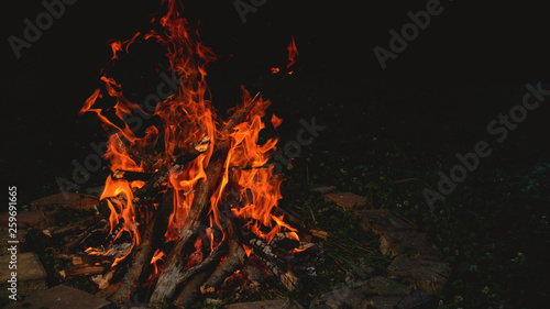 CLOSE UP: Large bright orange campfire burning inside a brick enclosed fire pit.