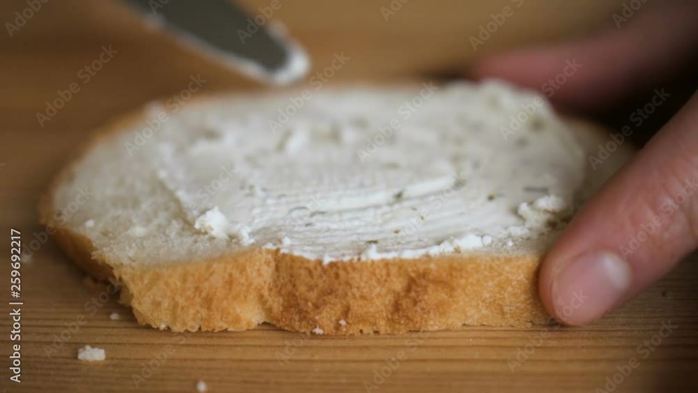 Man spreading butter on rye dry toast with a knife. Person spreading creamy butter on a piece of bread. Close up of male hands spreading butter on bread in kitchen, slow motion. Man spreading butter on rye dry toast with a knife. Person spreading creamy butter on a piece of bread. Close up of male hands spreading butter on bread in kitchen, slow motion.