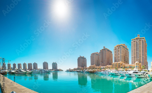 Panorama of luxury residential buildings of Pearl Qatar and white yachts at Porto Arabia marina. Doha, Qatar