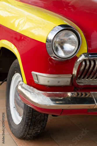 Right front wheel and headlight. Replicas of Russian cars. Halogen lighting at the yellow-red car.