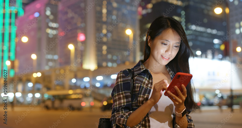 Woman use of mobile phone in the city at night