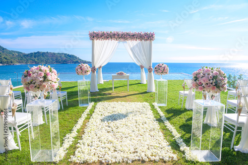 Wedding ceremony. Arch, decorated with flowers on the lawn, beach background, sea in summer.