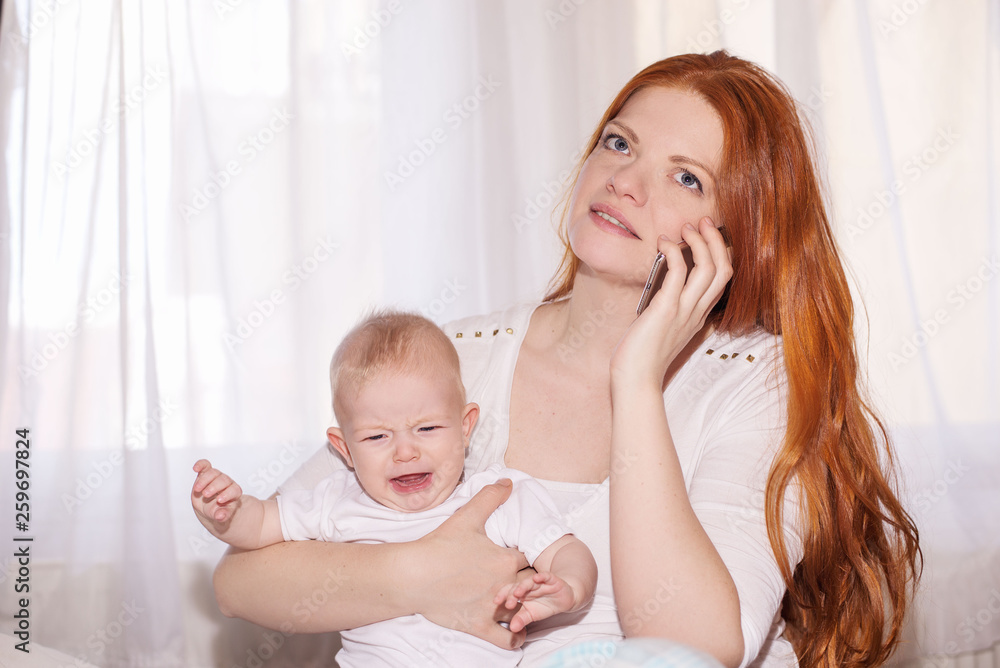 Young mother with baby sits and uses the phone Young mother with baby sits and uses the phone