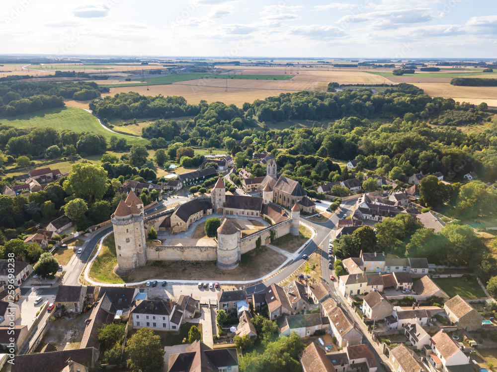 Medieval castle with fortified walls, towers and donjon in rural village in France, aerial view from drone of renovated fortress from middle age, scenic landscape, sunny summer, Blandy les Tours