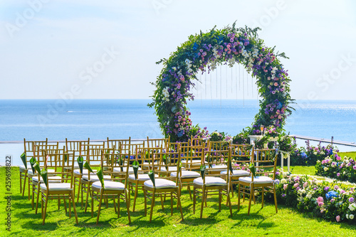 Wedding ceremony. Arch, decorated with flowers on the lawn, beach background, sea in summer.