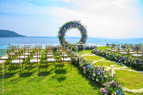 Wedding ceremony. Arch, decorated with flowers on the lawn, beach background, sea in summer.