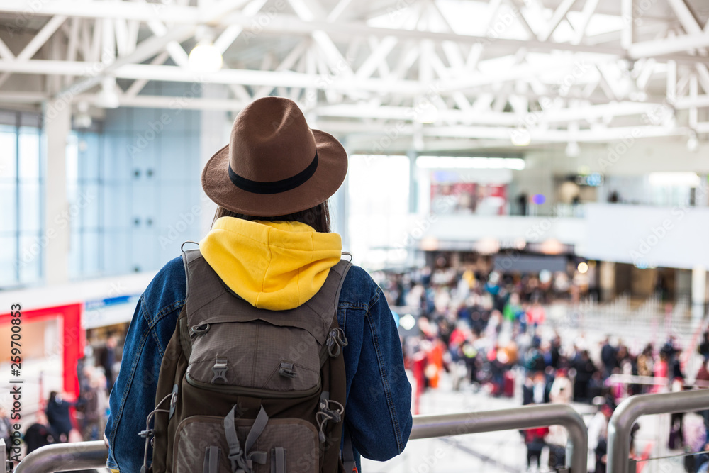 Young female traveller in hat with backpack over modern airport interior Young female traveller in hat with backpack over modern airport interior