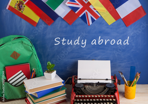 typewriter, blackboard with text "Study abroad", flags of Spain, France, Great Britain and other countries, backpack, books, stationery