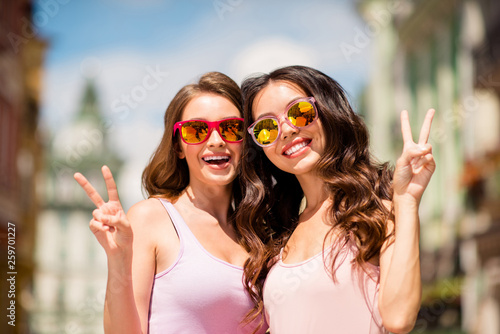 Close up photo charming cute trendy pretty hairstyle best millennial travel trip long hair spring pastel clothing modern spec travel enjoy free time laugh make v-signs satisfied joy town center