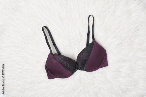 Purple bra with black lace on white fur. Flat lay. Fashion lingerie concept.