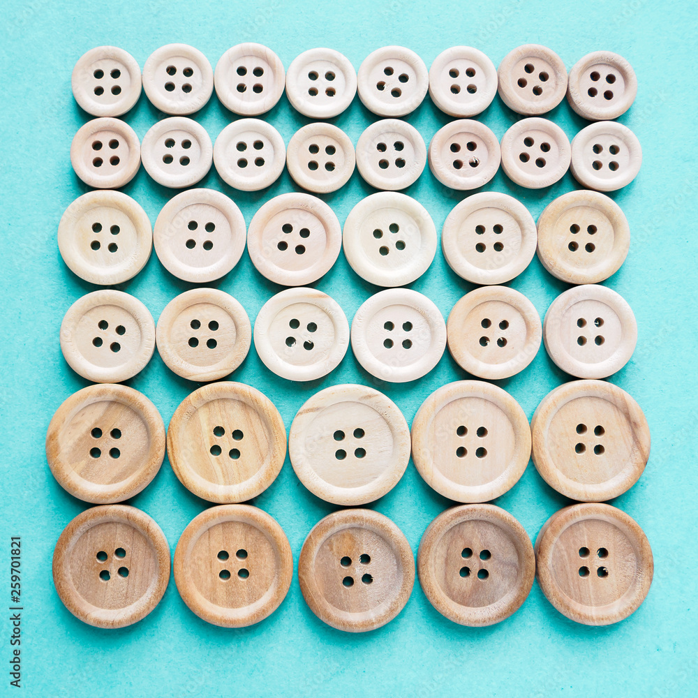 group of large and small beige wooden buttons in row on blue background group of large and small beige wooden buttons in row on blue background
