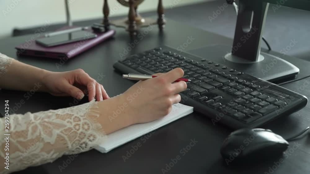 Female Making Notes in Notebook and Typing on PC Female Making Notes in Notebook and Typing on PC