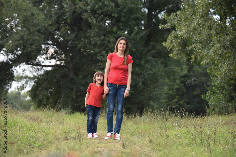 Portrait of Happy mom play with a son in park. Mother and son in red t-shirt playing outside Portrait of Happy mom play with a son in park. Mother and son in red t-shirt playing outside